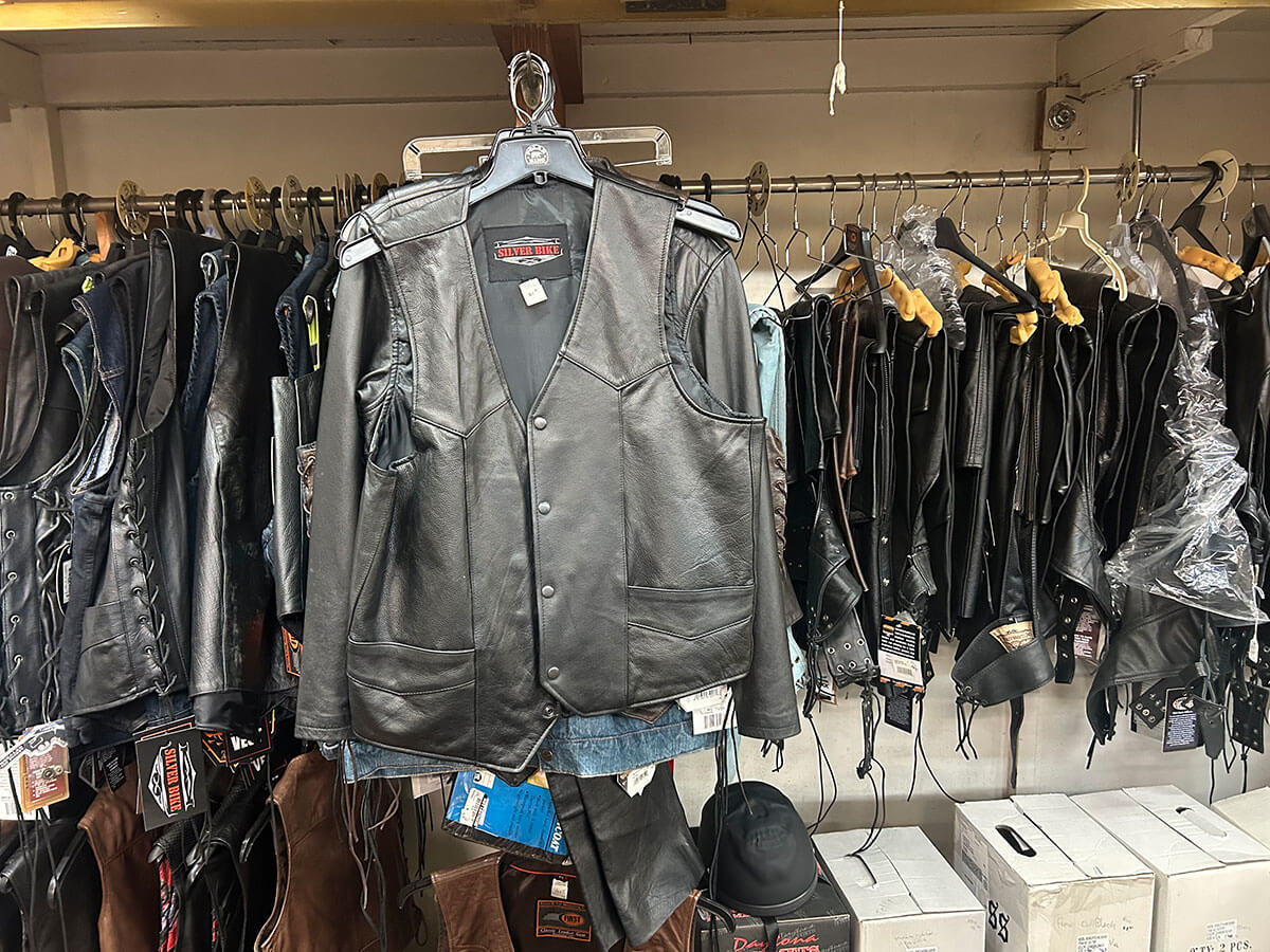 Black leather motorcycle vests on hangers.